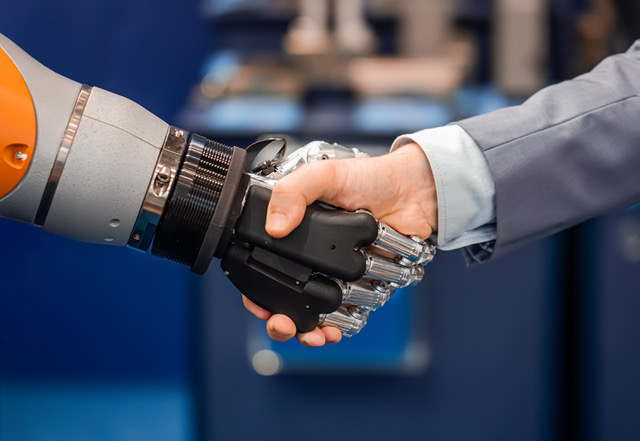 Hand of a businessman shaking hands with a Android robot.